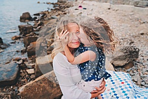 Portrait of happy mother and daughter spending time together on the beach on summer vacation. Happy family traveling, cozy mood.