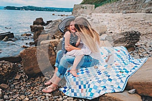 Portrait of happy mother and daughter spending time together on the beach on summer vacation. Happy family traveling, cozy mood.