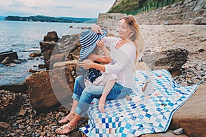 Portrait of happy mother and daughter spending time together on the beach on summer vacation. Happy family traveling, cozy mood.