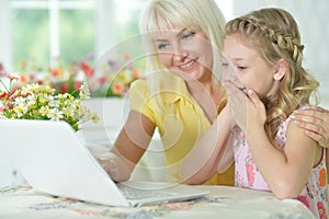 Portrait of happy mother and daughter using laptop