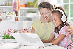 Portrait of happy mother and daughter using laptop together