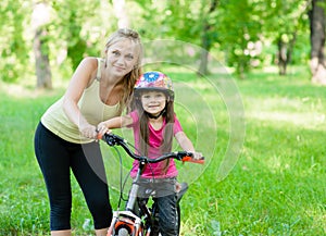 Portrait of a happy mother embracing daughter who learns to ride