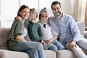 Portrait happy mother and father with kids sitting on couch