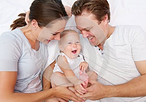 Portrait of a happy mother and father playing with cute baby