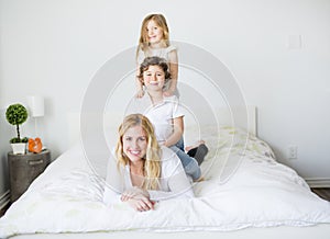 Portrait of a happy mother and her children lying on a bed