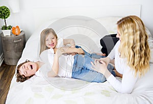 Portrait of a happy mother and her children lying on a bed