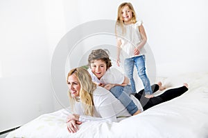 Portrait of a happy mother and her children lying on a bed