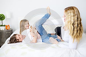 Portrait of a happy mother and her children lying on a bed