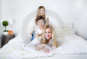 Portrait of a happy mother and her children lying on a bed