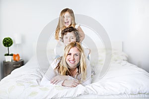 Portrait of a happy mother and her children lying on a bed