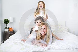 Portrait of a happy mother and her children lying on a bed