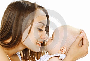 Happy mother holding on hands and kissing her little sleeping baby on a white background