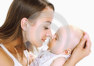 Happy mother holding on hands and kissing her little sleeping baby on a white background