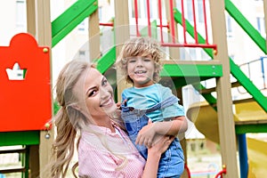 portrait of happy mother holding on hands smiling little son