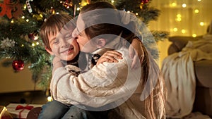 Portrait of happy mother kissing her smiling son in cheek while celebrating Christmas or New Year