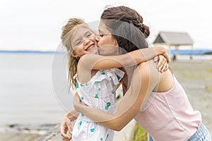 Portrait of happy mother and little daughter on sunny beach