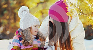 Portrait of happy mother and little girl child playing in winter over a snowy background