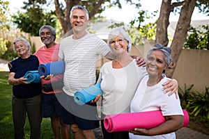 Portrait of happy multi-ethnic friends carrying exercise mats photo