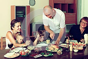 Portrait of happy multigeneration family eating chicken with wi