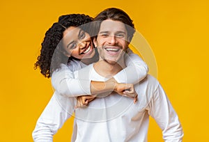 Portrait of happy multiracial couple cuddling and smiling at camera