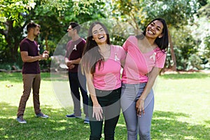 Portrait of happy multiracial female friends wearing breast cancer awareness ribbons at park