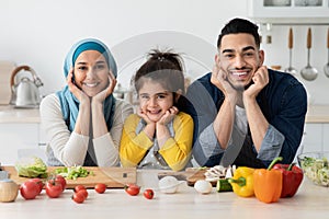 Portrait Of Happy Muslim Family Of Three Posing While Cooking In Kitchen