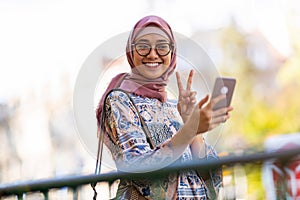 Portrait of a happy Muslim woman taking a selfie with her mobile phone