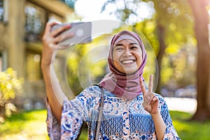 Portrait of a happy Muslim woman taking a selfie with her mobile phone