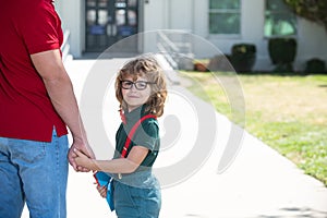 Portrait of happy nerd pupil holding teachers hand. School boy going to school with father. Parent with child in front