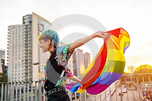 Portrait of happy non-binary person waving rainbow flag