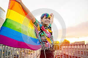 Portrait of happy non-binary person waving rainbow flag