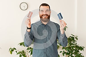 Portrait of happy office worker man showing two credit card, red and blue debit card