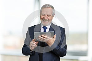 Portrait of happy old businessman using tablet.