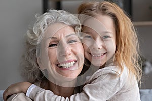 Portrait of happy old grandmother and little granddaughter hugging
