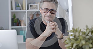 Portrait of happy older man in glasses at desk at home