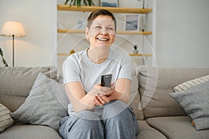 Portrait of happy older woman changing channel on television.