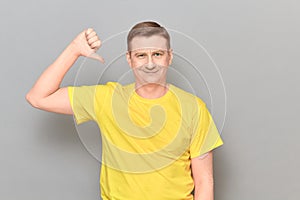 Portrait of happy optimistic man giving thumb down sign of dislike