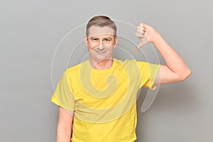 Portrait of happy optimistic man giving thumb down sign of dislike