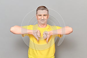 Portrait of happy optimistic man giving thumbs down signs of dislike