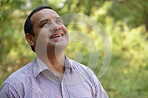 Portrait of happy overweight Indian businessman at the park outdoors