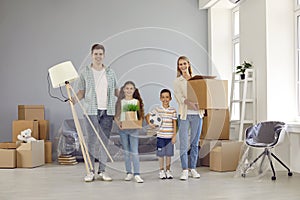 Portrait of happy parents and children with their things in their hands in their new apartment.