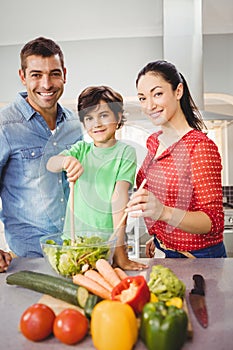 Portrait of happy parents and son preparing salad