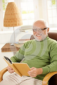 Portrait of happy pensioner relaxing with book