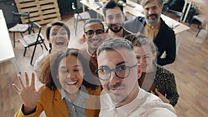 Portrait of happy people colleagues taking selfie in office with thumbs-up hand gesture looking at camera