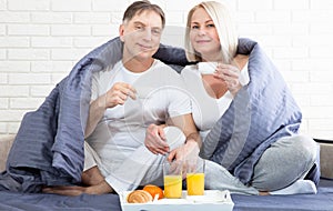 Portrait of happy playful couple relaxing in comfortable cozy bed looking at each other, cheerful man and woman having
