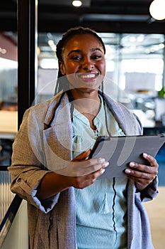 Portrait of happy plus size african american casual businesswoman using tablet in office