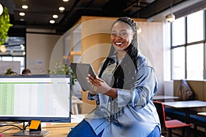 Portrait of happy plus size african american casual businesswoman using tablet in office