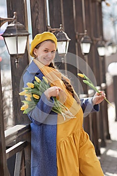 Portrait of a happy pregnant woman with a bouquet of yellow tulips on a walk in spring.
