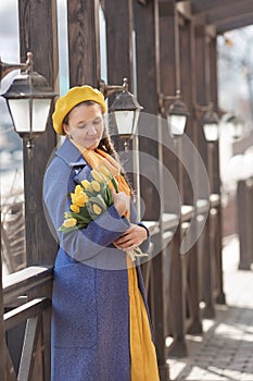 Portrait of a happy pregnant woman with a bouquet of yellow tulips on a walk in spring. Flowers for International