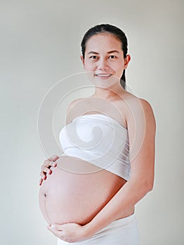 Portrait of happy pregnant woman holding her hands on her belly